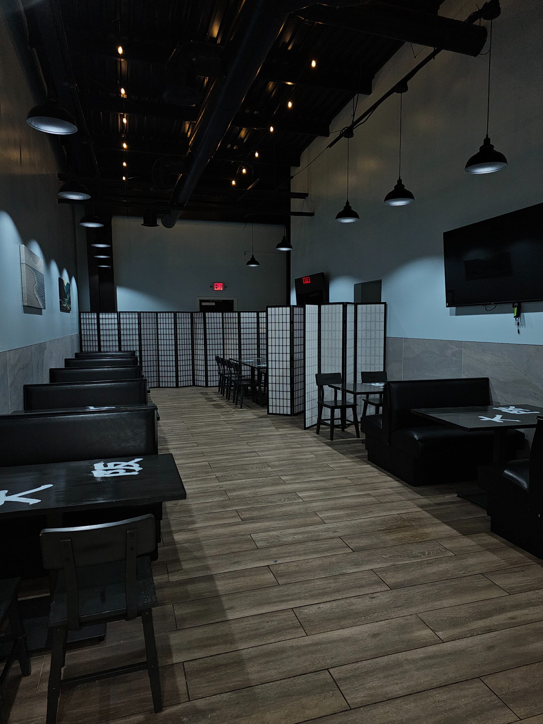 Black tables with hand-painted white kanji and shoji screen dividers in the Osaka Express dining room